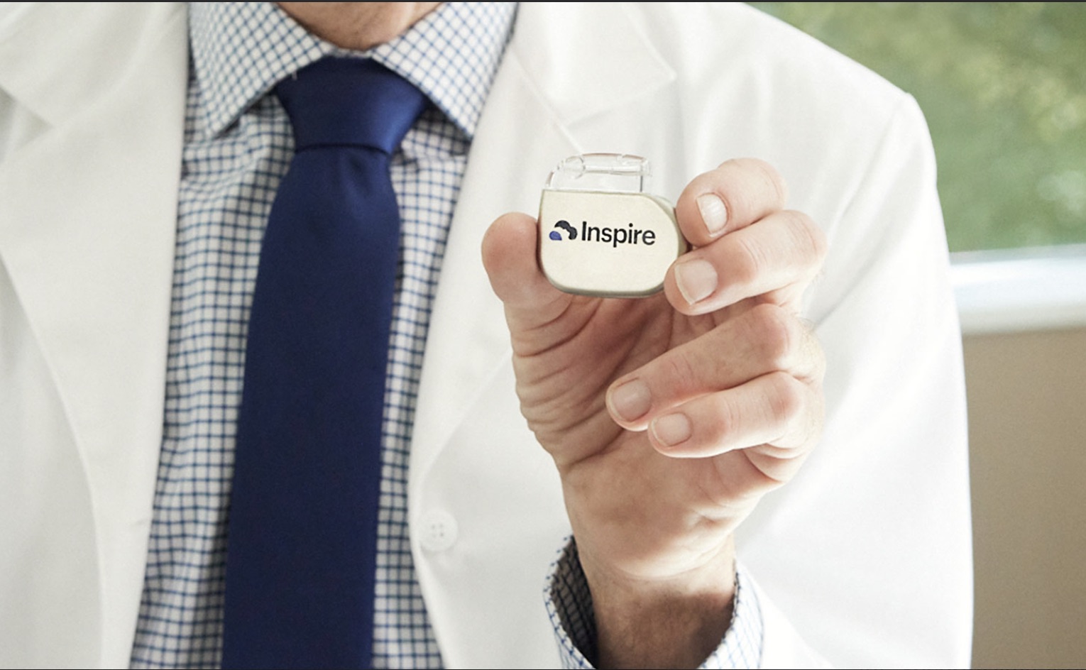 A clinician holding the Inspire device